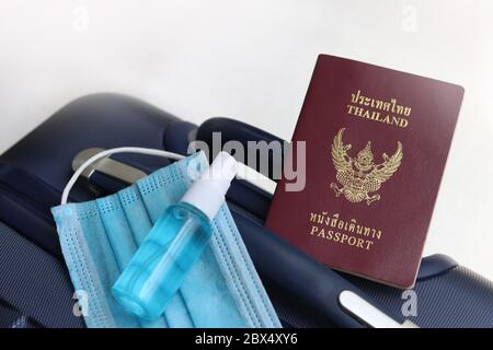 Thai passport on suitcase with medical mask and hand sanitizer spray. Lifestyle and travel concept in New Normal after Covid-19 / Coronavirus pandemic. Stock Photo