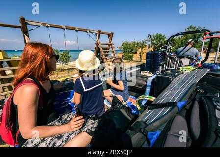 Family riding a tractor trailer with suitcases and luggage. Family on vacation is using transport or transfer from airport or a port to selected apart Stock Photo