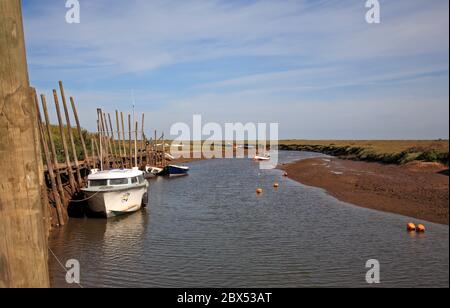 A view of the quay and boat moorings at the west end of the North Norfolk harbour at Blakeney, Norfolk, England, United Kingdom, Europe. Stock Photo