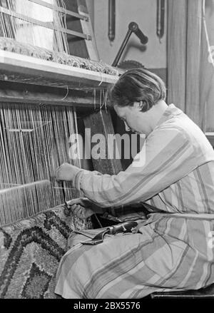 Training at a higher municipal technical school for the textile trade or also "School of Fashion": here a trainee is learning the technique of knotting carpets on a carpet knotting machine. Stock Photo