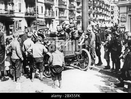 Children admire a car in Berlin. They are mostly barefoot. Stock Photo