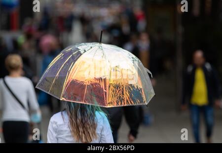 05 June 2020, Baden-Wuerttemberg, Stuttgart: A woman walks through Königsstraße with an umbrella that shimmers in colour. Photo: Tom Weller/dpa Stock Photo