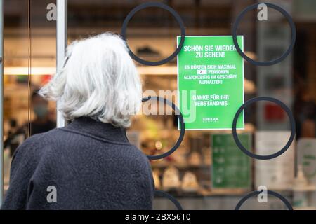 05 June 2020, Baden-Wuerttemberg, Stuttgart: A woman stands in front of a sign saying 'Nice to see you again! A maximum of 7 people are allowed in the shop at any one time! Thank you for your understanding' in Königsstraße. Photo: Tom Weller/dpa Stock Photo