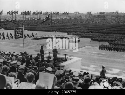 Adolf Hitler gives a speech from the pulpit of the Zeppelin grandstand to the approximately 38,000 men of the Reich Labor Service who have taken up their posts. On the left behind him is Konstantin Hierl. On the right side of the picture is the photographer Heinrich Hoffmann. On the left are the RAD flag wavers, in the middle the female youth of the Reich Labor Service. Stock Photo