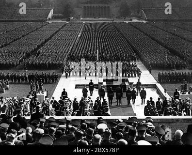 Adolf Hitler speaks from the pulpit of the Luitpold Arena to the Nazi organizations that had lined up for roll call on the Nuremberg Nazi Party Rally Grounds. In the background is the Ehrenhalle. On the left and right are two film teams. Stock Photo