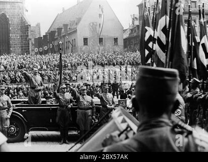 During the Reich Party Congress of Labor, Adolf Hitler takes the salute of the Nazi formations in his Mercedes on Nuremberg's main market square, the so-called Adolf-Hitler-Platz. In front of the car, Franz Pfeffer von Salomon, Hermann Goering, Adolf Huehnlein and Viktor Lutze (from right). Behind them, the grandstand. Stock Photo