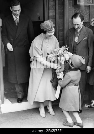 Queen Elizabeth receives a bouquet of flowers from a little girl named Frances Neil, while she and her husband King George VI visit Hilcot House in Clarissa Street from Kingsland Road through the poor district of Shoreditch. Stock Photo