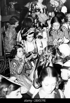 Princess Margaret (front left, with a horn) with her sister Princess Elizabeth ( behind, on the left) during a carnival party in London. Stock Photo
