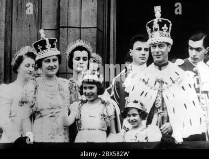 After the coronation, Queen Elizabeth, Princess Elizabeth, Princess Margaret Rose and King George VI stand on the balcony of Buckingham Palace with the rest of the royal family and wave to the crowd. Stock Photo