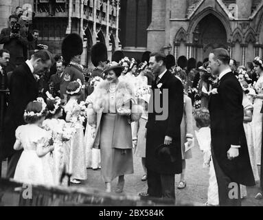 Queen Elizabeth, King George VI, Princess Margaret Rose and Princess Elizabeth (undercover) at the wedding of the Queen's niece, Miss Bowes-Lyon and Lieutenant-Colonel Thomas William Arnold Anson at Westminster Abbey. The bridesmaids are standing at the edge. Stock Photo