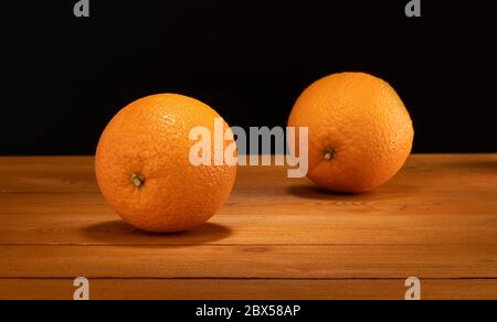 two oranges on wooden table and black background Stock Photo