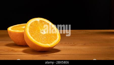 Halves oranges on a black background. Space for text. Sliced citrus fruits on a wooden table. Stock Photo