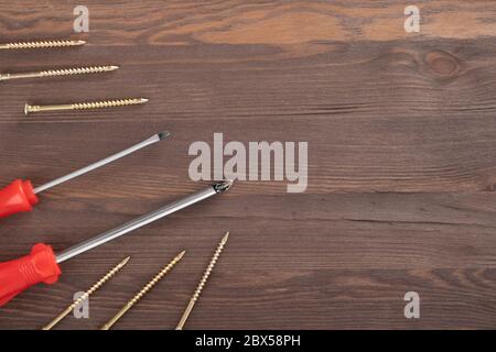Screwdrivers with self-tapping screws on wooden background. Free space for text. Stock Photo