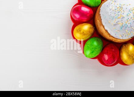 Easter cake kulich. Traditional Easter sweet bread and easter colorful eggs on plate on white wooden background. Copy space. Stock Photo