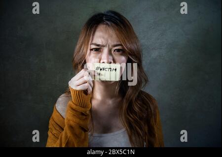 young sad and desperate Asian Korean student woman holding message paper as victim of abuse suffering domestic violence and bullying feeling helpless Stock Photo