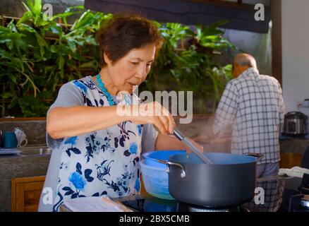 lifestyle portrait of senior happy and beautiful retired Asian Japanese couple cooking together at home kitchen enjoying preparing meal relaxed in age Stock Photo