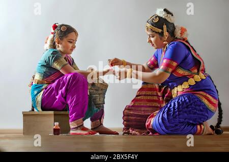 Bharatnatyam dancer applying alta on her student’s palms. Stock Photo