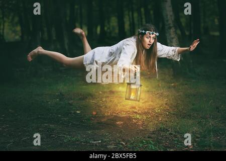 Young woman with shocked expression finds herself flying in the woods. Fantasy and surreal Stock Photo