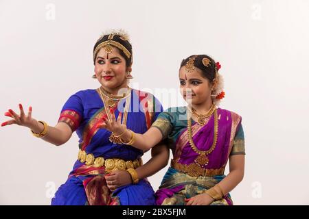 Bharatnatyam dancer and her student performing gracefully through their expressions and hands. Stock Photo