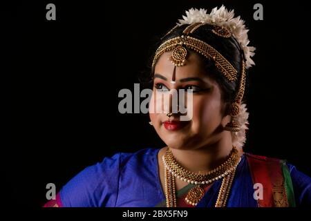 Beautiful bharatnatyam dancer standing in front of a dark background. Stock Photo