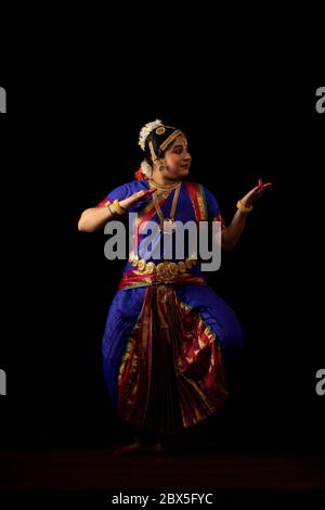 Bharatnatyam dancer standing in araimandi position in front of a dark background. Stock Photo