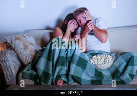 young mixed race attractive couple with Asian Korean woman and white man enjoying together watching television horror movie scared girlfriend in panic Stock Photo