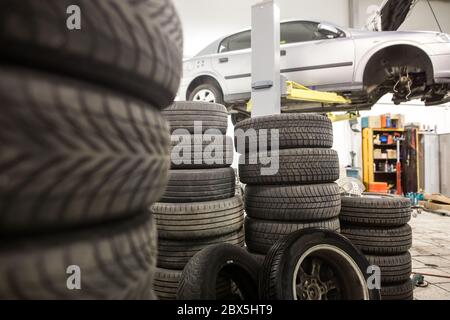 View to car service, a lot of wheels ready for changing and car on the hydraulic jack, car service center Stock Photo