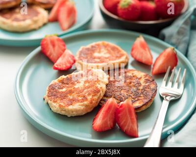 Sweet cheese pancakes on plate served strawberries. Cottage cheese pancakes, syrniki, ricotta fritters, curd fritters, Copy space for text or design. Stock Photo