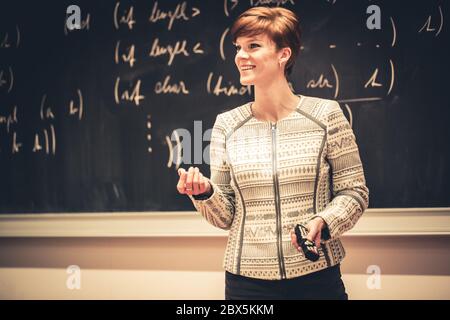 Teacher and action, presenting new curriculum to pupils on blackboard, looking strict, education concept Stock Photo