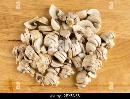Sliced champignons on a cutting board. Edible mushrooms broken into pieces. Stock Photo