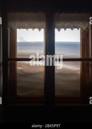 View from inside a snow covered mountain hut through a window with snow in front Stock Photo