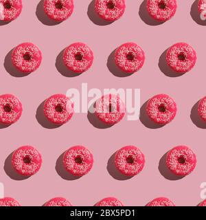 Pink donut with sprinkles seamless pattern, sweet glazed dessert food on pink minimal background, top view Stock Photo
