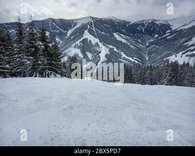 Scenic view of snow covered mountains from a slope of Viehofen ski route in the ski region Saalbach-Hinterglemm in the Austrian alps against cloudy sk Stock Photo