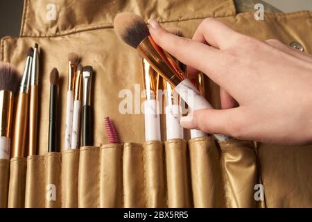 Cosmetic Makeup Brush in female hand on recruitment background. Stock Photo