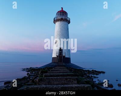 The Point of Ayr Lighthouse on a very quiet beach at Talacre, North Wales against a blue and purple sky at sunset on new years day Stock Photo