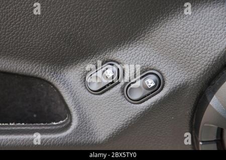 Two black window adjustment buttons with white marks on the plastic panel of the door next to the handle of an old Russian car close-up in front of a Stock Photo