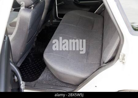 The rear row of passenger seats covered with gray cloth and with a clean rubber black rug underfoot in an old Russian car after dry cleaning prepared Stock Photo