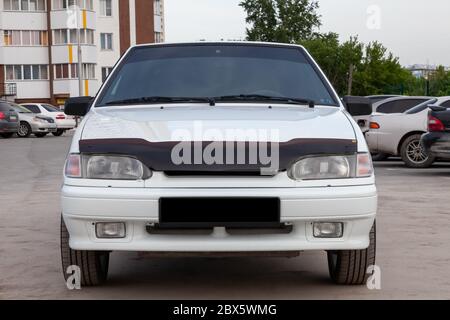 Novosibirsk, Russia - 05/20/2020: front part of a white Russian car brand VAZ model 2114 on the background of an apartment building and cars with dire Stock Photo