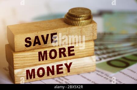 Save More Money on wooden cubes and 100 Euro bills and coins. Investment and saving financial concept. Selective focus