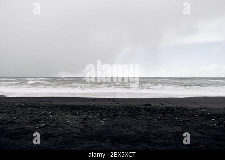 Cloudy skies, Atlantic Ocean waves and black sand on Vik beach, Iceland. Stock Photo