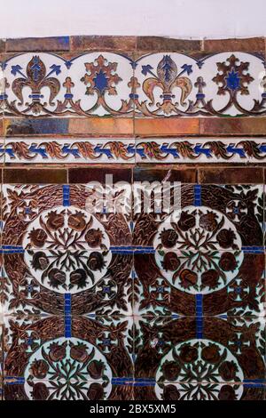 Wall tiles with traditional geometrical floral motive, but more modern style thanks to a high glossy metal finish. Wall in an abandoned house. Dar Cai Stock Photo