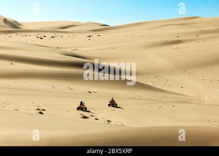 Quad driving people - two happy bikers in sand desert dunes, Africa, Namibia, Namib, Walvis Bay, Swakopmund. Stock Photo
