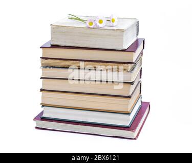 a stack of old books. bouquet of flowers from daisies on a white background. Stock Photo