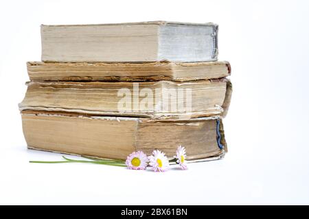 a stack of old books. bouquet of flowers from daisies on a white background Stock Photo
