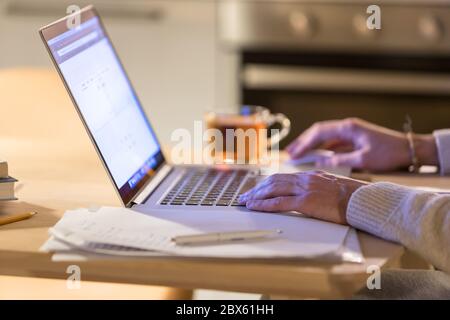 Closeup of man working at home using laptop, , using computer mouse, cup of tea blurred on background. Freelancer, remote work, freelace Stock Photo