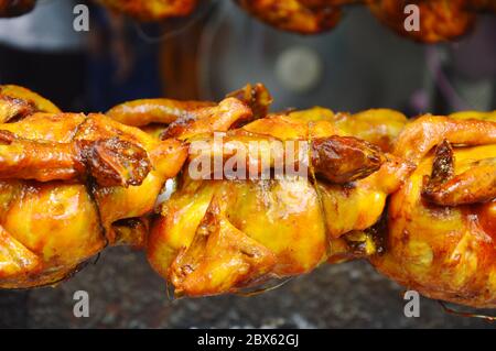 roasted chicken stabbing in iron and rolling on stove Stock Photo
