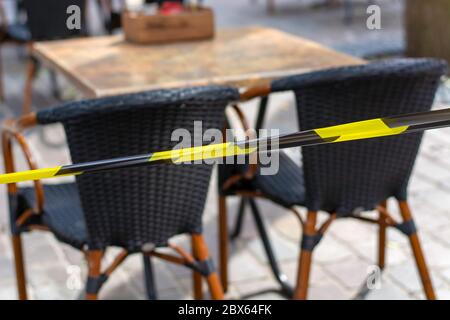 Terraces in city open again. Safety barrier tape on terrace ensures that safe social distance can be kept between tables and chairs during coronavirus Stock Photo