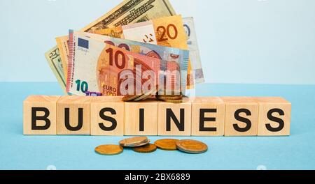 BUSINESS word written on wood cubes on the background of various banknotes. Financial concept Stock Photo