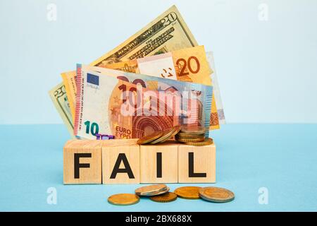 Fail word written on wood cubes on the background of various banknotes. Financial concept Stock Photo