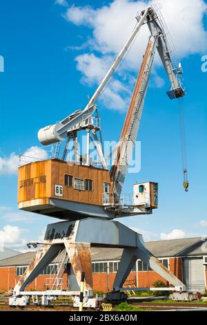 An old, orange colored, discarded dockside crane at a sunny day. Stock Photo
